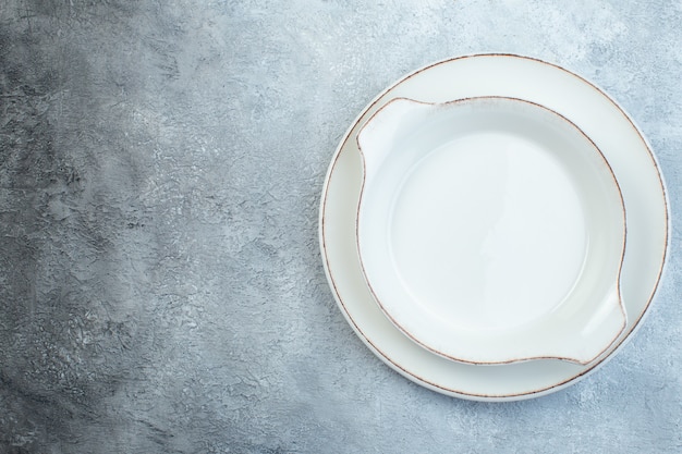 Empty white soup plates on the left side on half dark light gray surface with distressed surface with free space