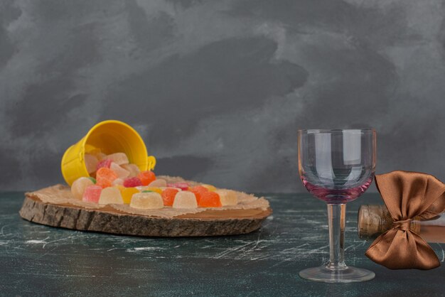 Empty wineglass with yellow bucket of jelly candies .