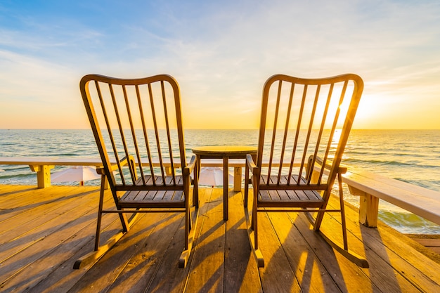 Empty wood chair and table at outdoor patio with beautiful tropical beach and sea