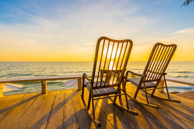 Empty wood chair and table at outdoor patio with beautiful tropical beach and sea