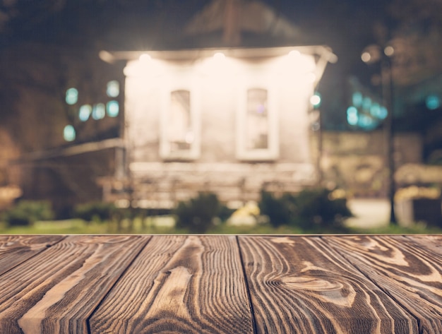 Free Photo empty wooden table in front of blurred house backdrop