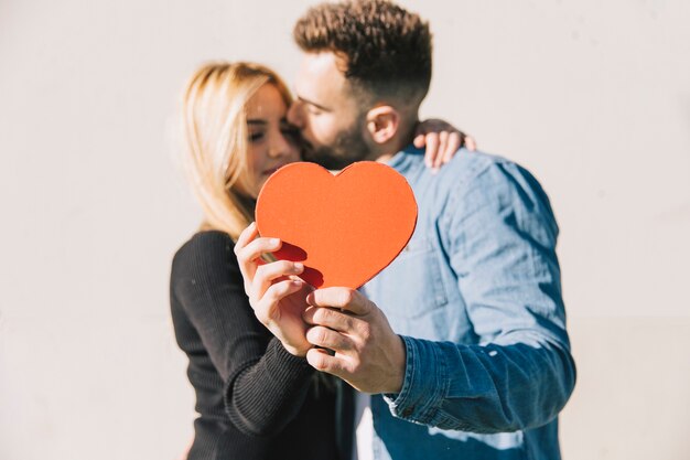 Enamored couple posing with red heart