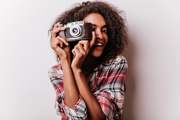 Enchanting black girl taking pictures with smile Indoor photo of carefree african lady with camera