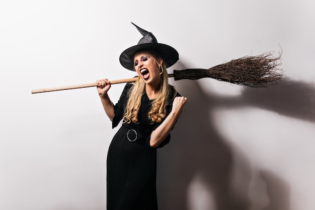 Enchanting witch in black outfit enjoying party. amazing blonde wizard with broom.