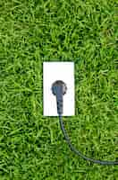 Free photo energy concept outlet in  fresh spring green grass