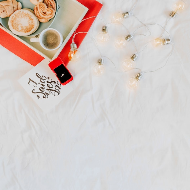 Engagement ring near breakfast and light garland