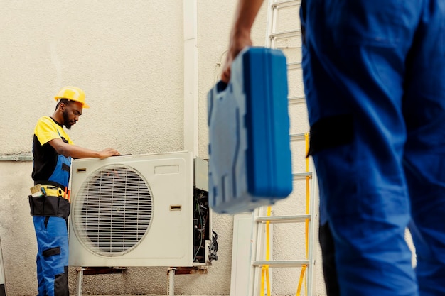 Free photo engineer arriving on location to help apprentice mend busted electric coils in damaged external air conditioner technicians comissioned to prevent internal parts breakdowns ensuring timely repair