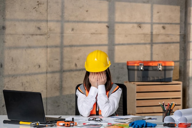 Engineer civil worker in helmet and vest smart young cute brunette girl covering face