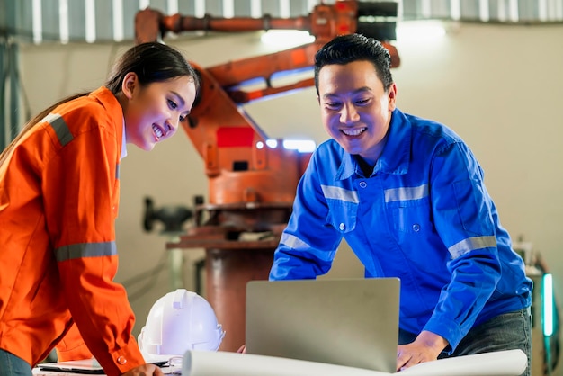 Engineer cooperation Two asian male and female technician maintenance inspect relay robot system with tablet laptop to control quality operate process work heavy industry 40 manufacturing factory