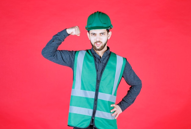 Free photo engineer in green uniform and helmet demonstrating his fist.