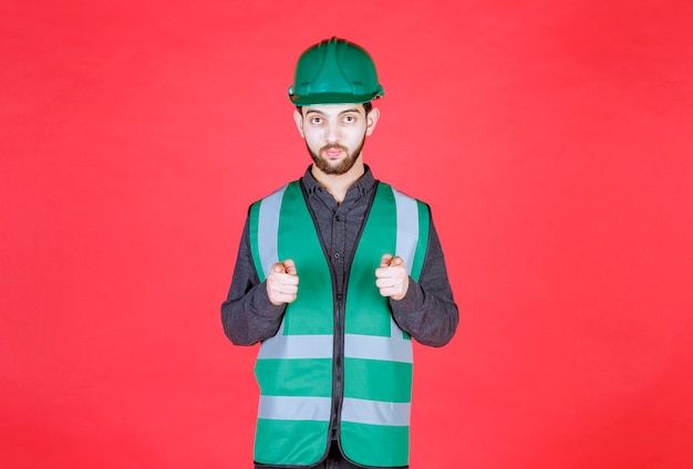 Free photo engineer in green uniform and helmet noticing the person ahead.