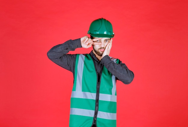 Free photo engineer in green uniform and helmet sending peace and friendship.