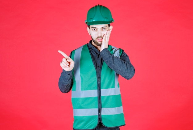 Engineer in green uniform and helmet showing left side. 