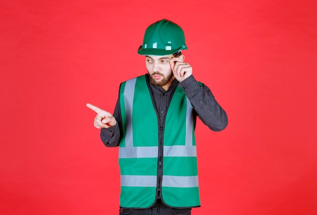 Free Photo engineer in green uniform and helmet showing left side. 