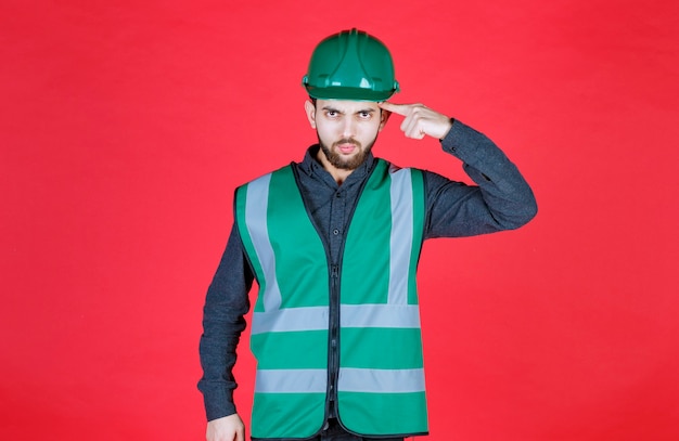 Free photo engineer in green uniform and helmet thinking and planning.