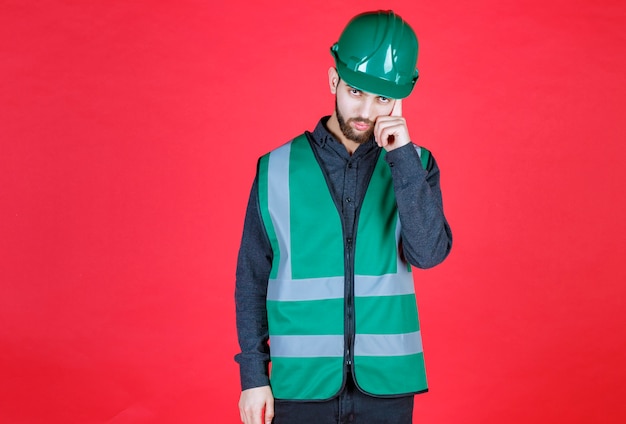 Free photo engineer in green uniform and helmet thinking and planning.