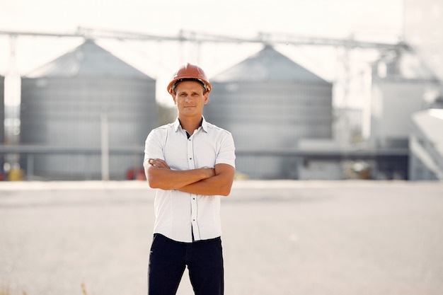 Engineer in a helmet standing by the factory