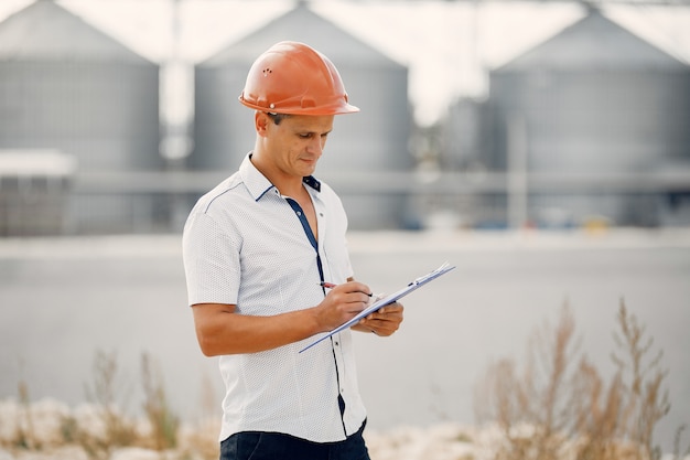 Engineer in a helmet standing by the factory