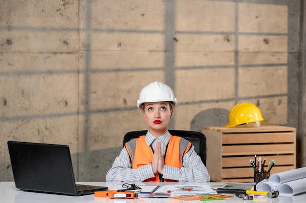 Engineer in helmet and vest civil worker smart young cute blonde girl praying