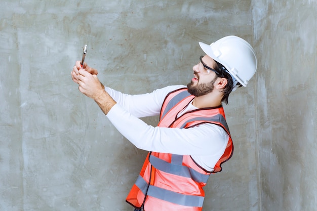 Free Photo engineer man in white helmet and protective eyeglasses holding metallic wrenches.