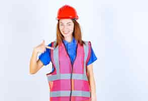 Free photo engineer woman in uniform and red helmet introducing herself.