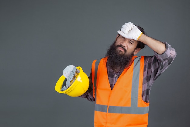 Free photo an engineering man wearing a yellow helmet wearing white gloves showed a gesture on a gray .