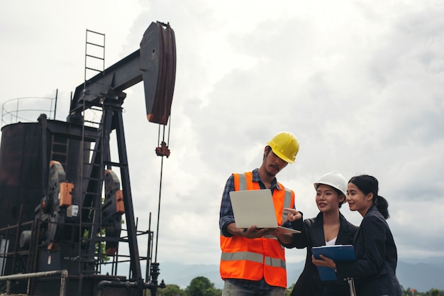 Free photo the engineering team stands beside working oil pumps with a sky .