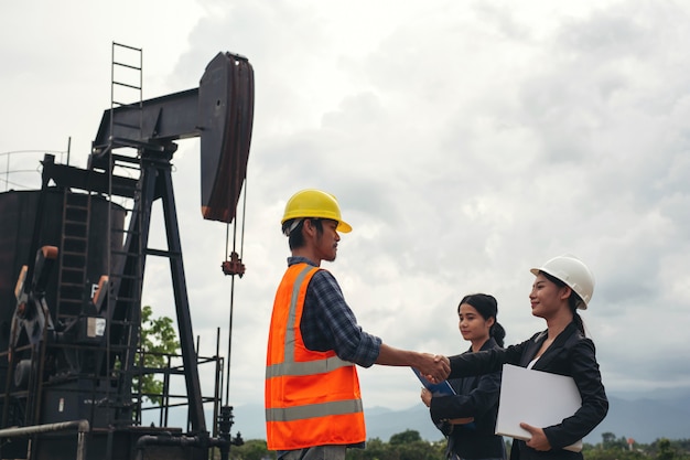 Free photo the engineering team stands beside working oil pumps with a sky .