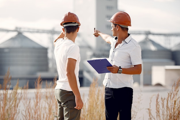 Free photo engineers in helmets standing by the factory