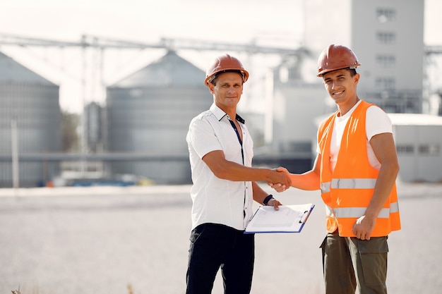 Engineers in helmets standing by the factory