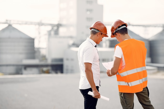 Engineers in helmets standing by the factory