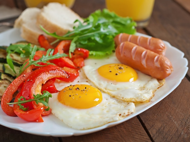 English breakfast - fried eggs, sausages, zucchini and sweet peppers