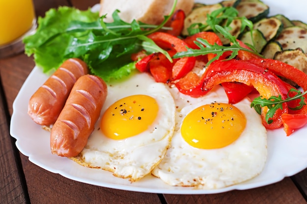 English breakfast - fried eggs, sausages, zucchini and sweet peppers