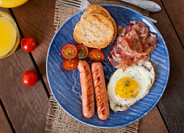 Free photo english breakfast - toast, egg, bacon and vegetables in a rustic style on wooden table