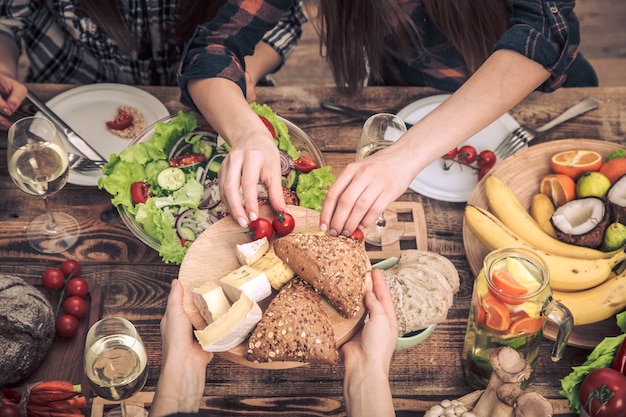 Enjoying dinner with my friends. Top view of a group of people dining together, sitting at a rustic wooden table, the concept of celebration and healthy home-cooked food