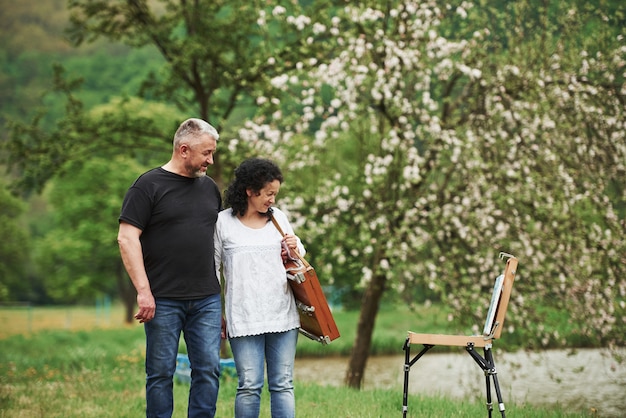 Enjoying the paint. Lovely mature couple have a walk in the park at leisure time