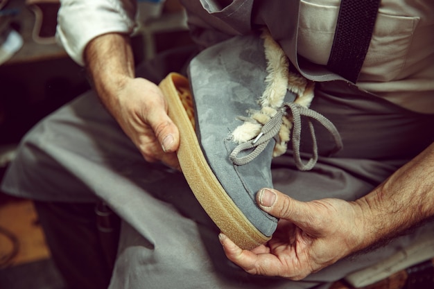 Free photo enjoying process of creation custom made shoes. workplace of shoe designer. hands of shoemaker dealing with cobbler tool, close up