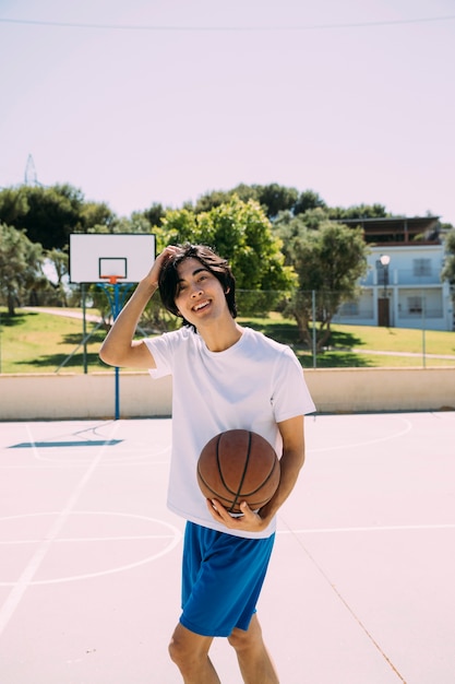 Free photo enthusiastic asian teen student playing basketball