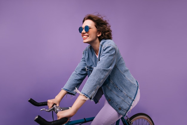 Enthusiastic female bicyclist having fun. Pretty caucasian girl sitting on bike and making funny faces.