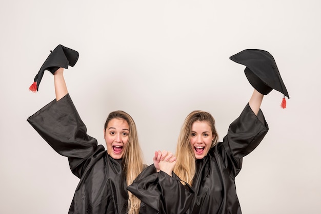 Free Photo enthusiastic graduates holding up trenchers 