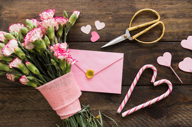 Envelope near bouquet of blooms with ribbon, scissors and candy canes