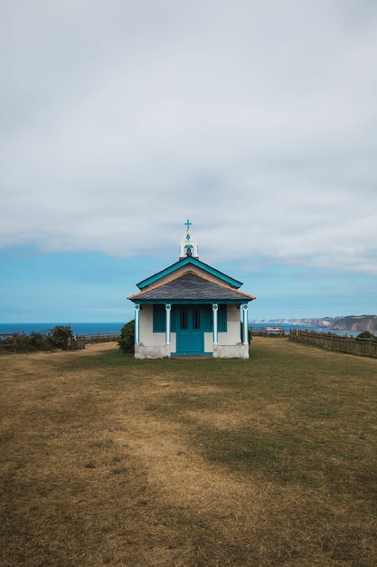 Free photo the ermita de la regalina surrounded by the sea under a cloudy sky in asturias, spain