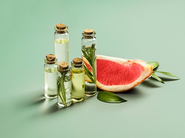 Free photo essential oil in glass bottle with fresh, juicy grapefruit and green leaves-beauty treatment.