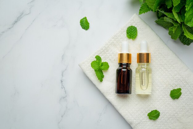 Essential oil of peppermint in bottle with fresh green peppermint