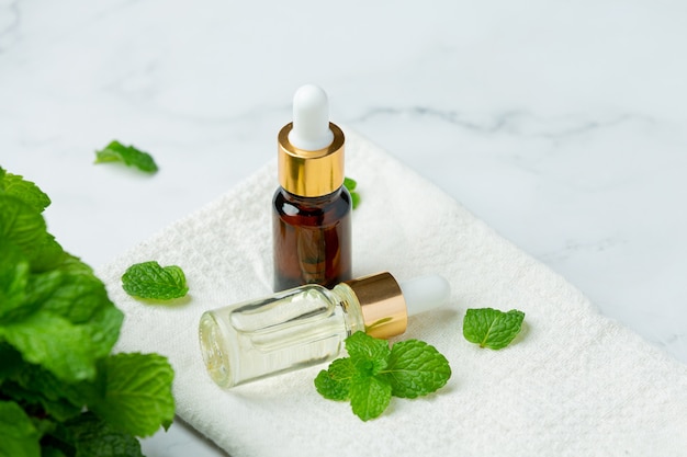 Essential oil of peppermint in bottle with fresh green peppermint