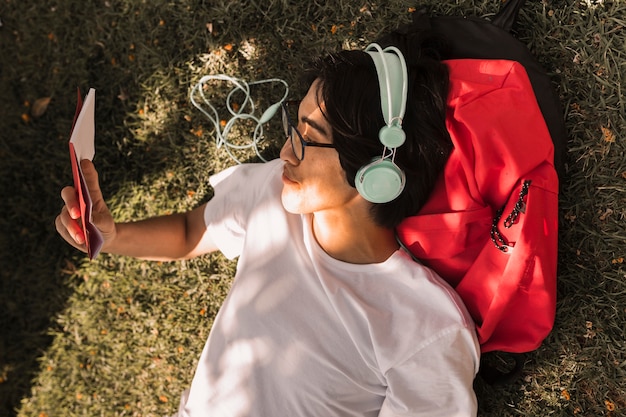 Free photo ethnic teen laying on ground with book