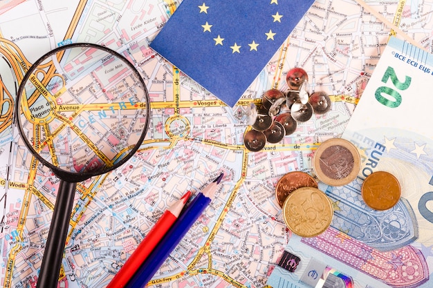 Free photo euro currencies with magnifying glass, pushpins, pencils and flag on world map