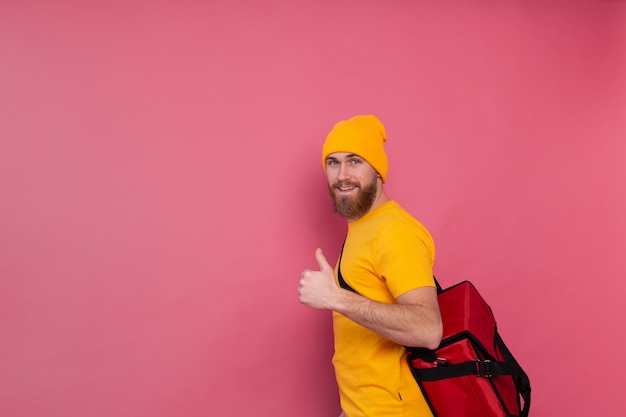 Free Photo european bearded delivery man with box with food smiling and showing thumb up on pink