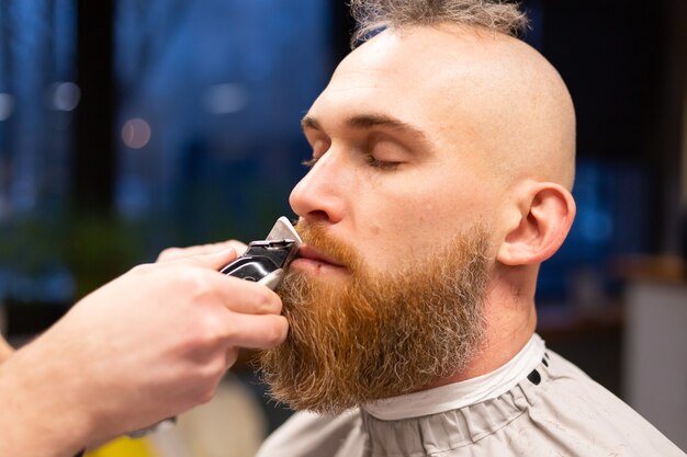 European brutal man with a beard cut in a barbershop