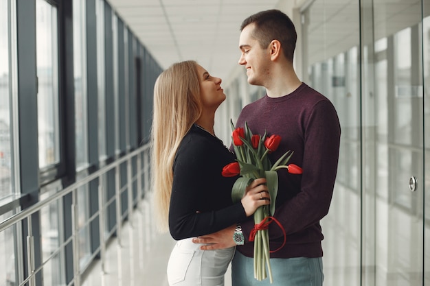 European couple is standing in a hall with a bunch of red tulips